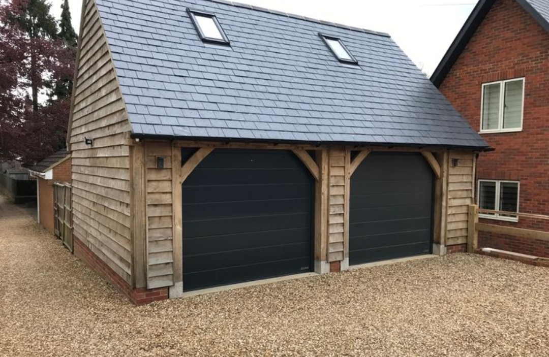 Completed two-bay oak garage with shingle cladding and a slate roof