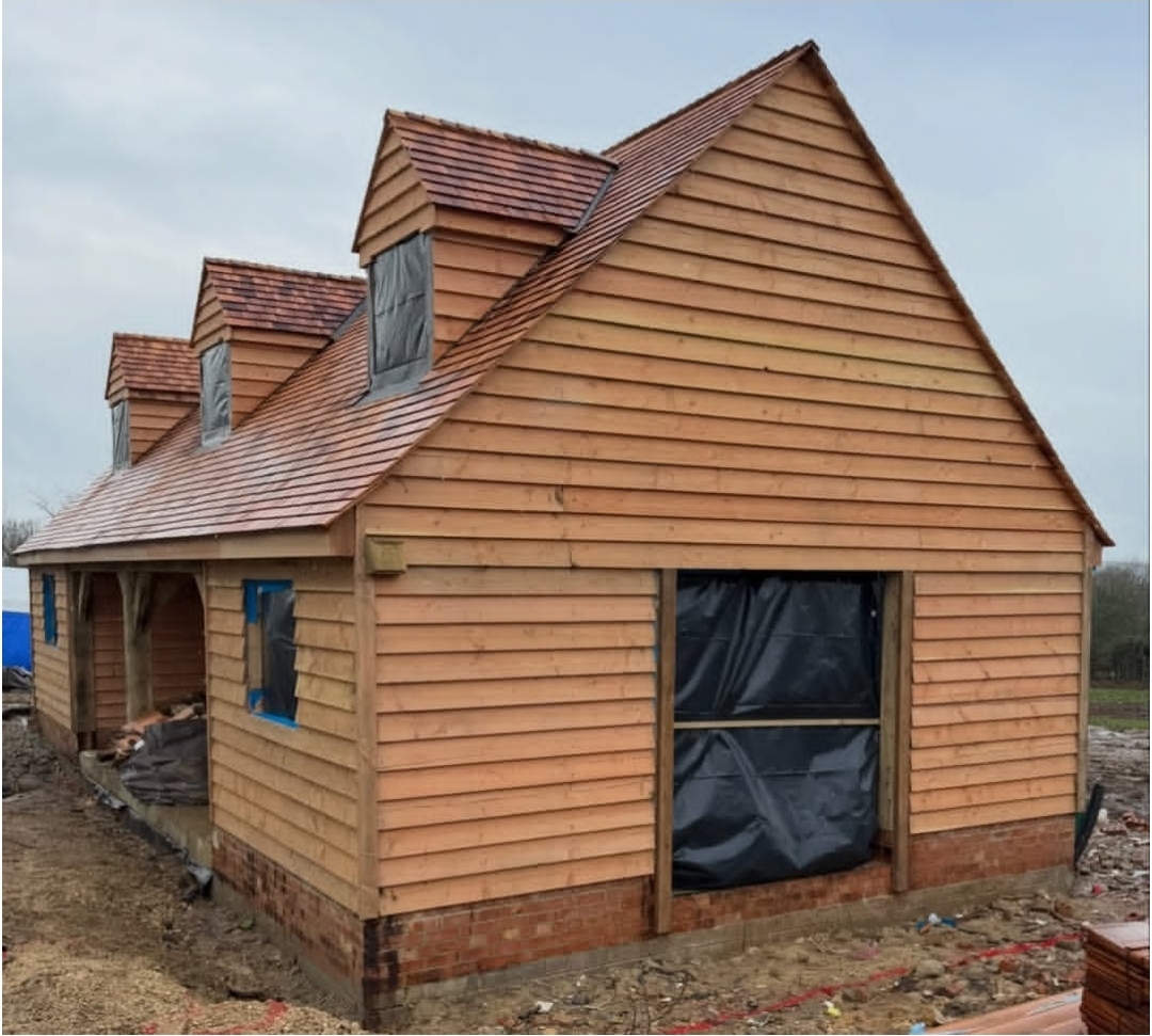 Clad oak outbuilding with three dormers photographed mid-build