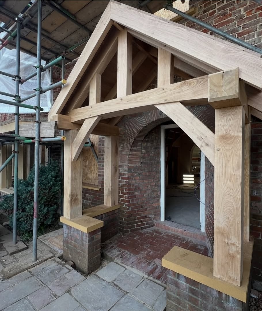 Solid oak porch frame against a period brick house before the roof went on