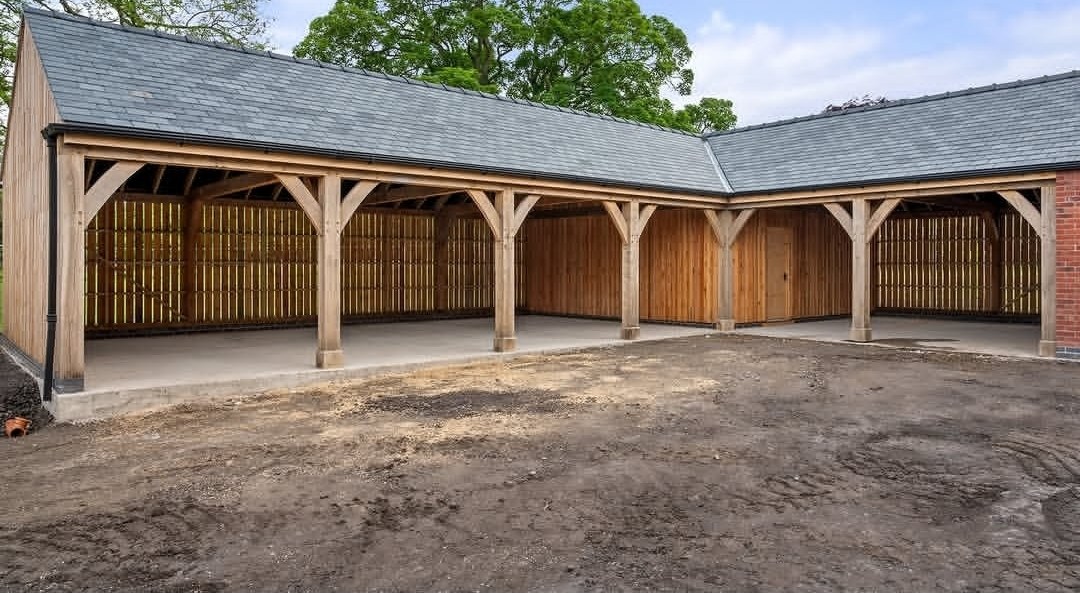 Completed open-bay oak cart lodge in an L shape under a slate roof