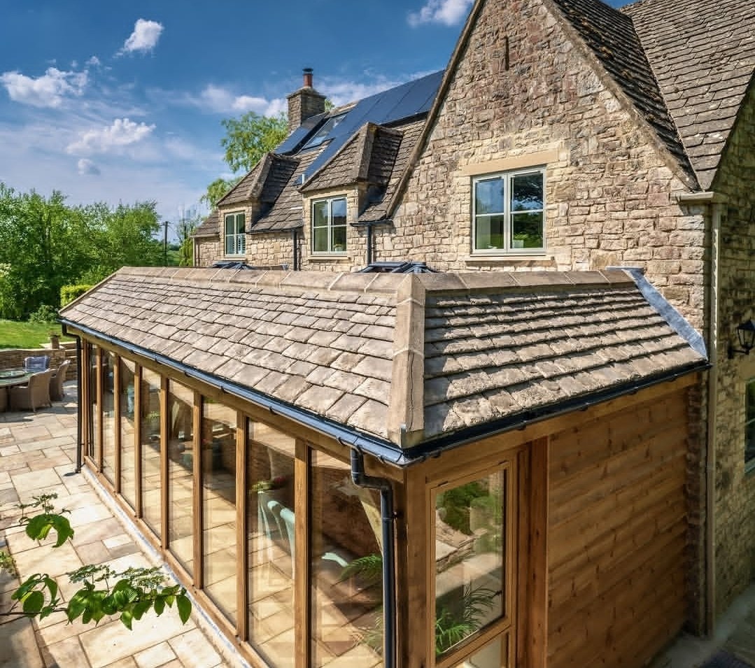 Glazed oak garden room with a stone tile roof added to a stone cottage