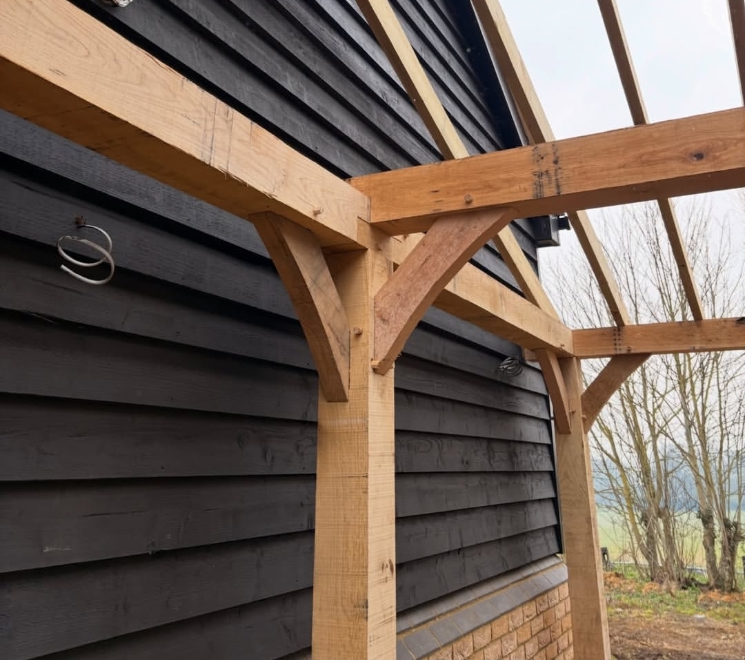 Close view of an oak lean-to frame with a curved brace against black boarding