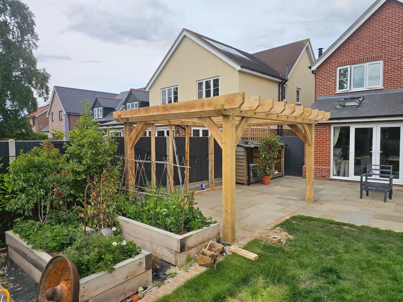 Completed oak pergola structure over patio area with integrated seating