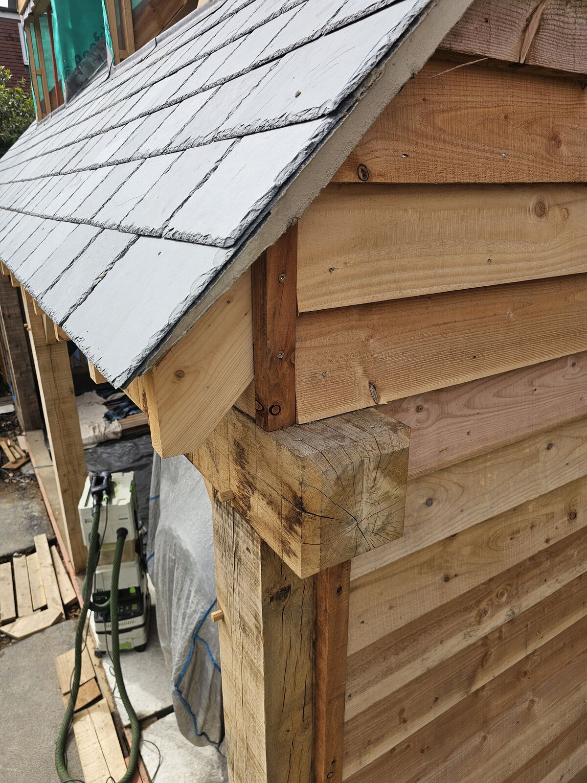 Heavy oak corner post meeting the rafters with a slate roof beyond
