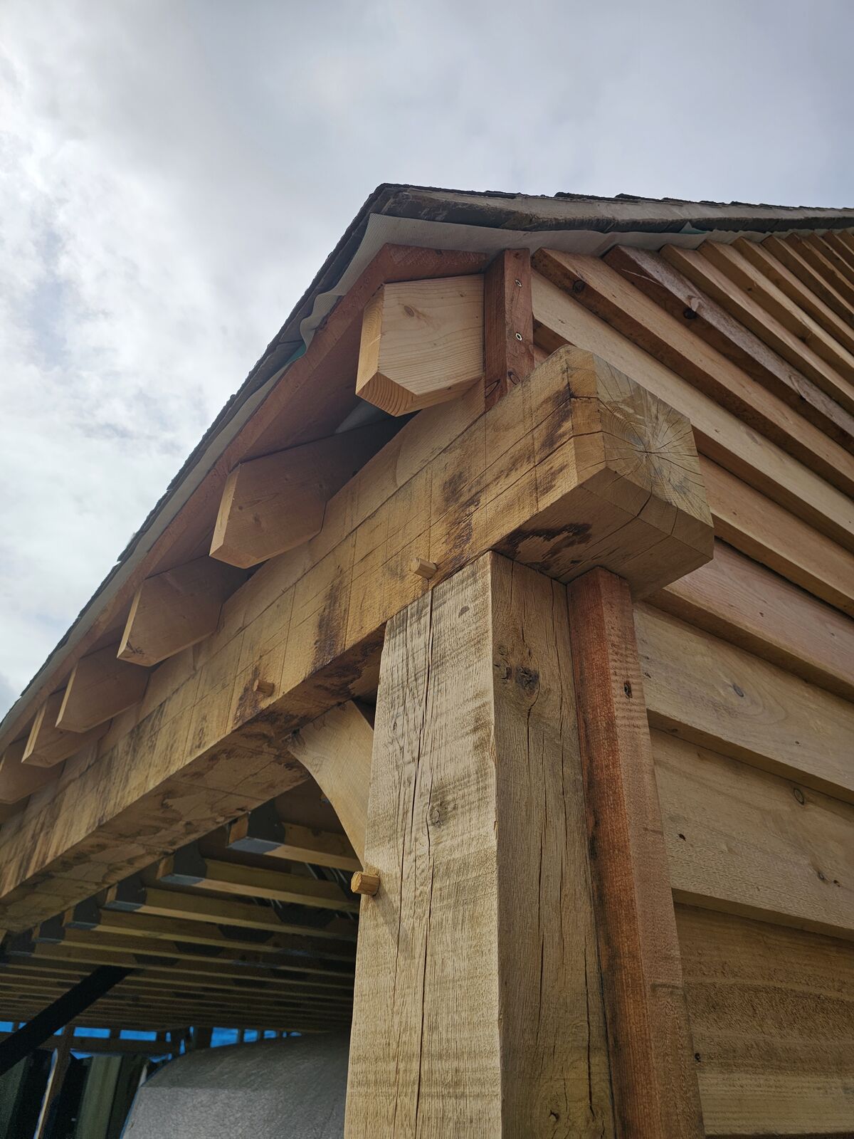 Hand-cut green oak corner post carrying the wall plate with exposed rafter feet above