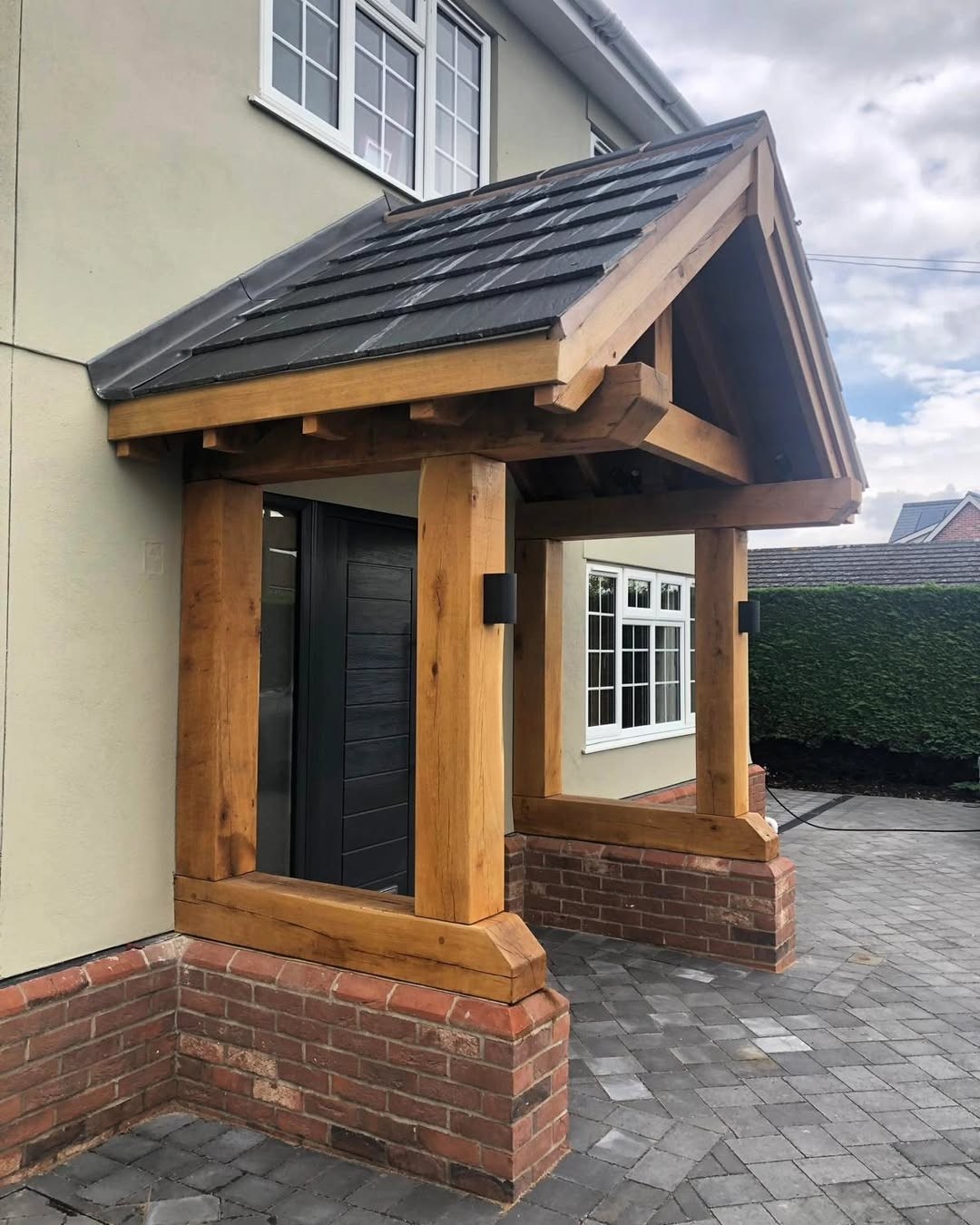 Solid oak porch with a slate roof on a rendered house with a brick plinth